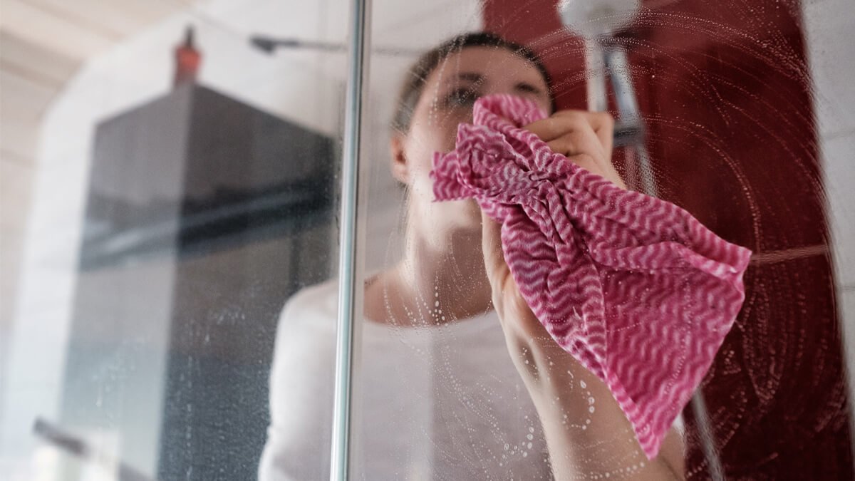 mujer limpiando la mampara de la ducha
